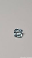 Close up photo of a single natural, untreated blue aquamarine gemstone octagon cut, 0.83 carat, VS clarity, 5.7x5.5mm size.