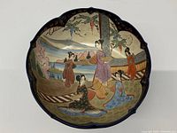 Full view of the antique Satsuma bowl with cobalt blue scalloped rim and painted geisha figures in garden setting.