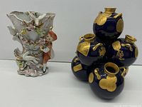 Shows the two antique vases: a white porcelain vase with figurine and floral decoration, and a blue vase cluster with gold motifs.