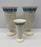 Front view of two larger and one smaller Wedgwood vases showing their size and decoration.
