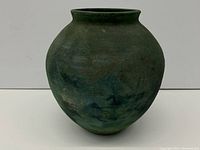 Front and side view of the round bulbous green-blue mottled pottery vase with narrow rim.