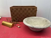 Photo showing wood lined basket, plaster planter bowl and brass tone metal lamp on red table