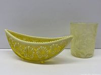 Side view of yellow patterned whimsy canoe and glass on white surface with plain background.