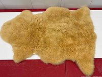 Full view of natural tan sheepskin throw rug with soft dense wool fleece and irregular natural shape.