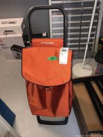 Front view of the orange Rolser shopping trolley showing the flap closure with a hook.