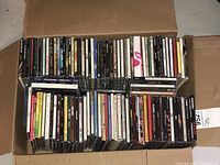 Full box top-down view showing many audio CDs packed neatly, spines visible, different genres and artists included.