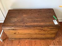 Full view of the wooden chest from the side showing the missing metal handle and worn wood surface.