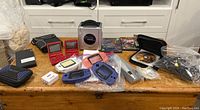 Wide view of all items on wooden table showing console, handhelds, games, upscaler and cables