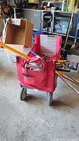 Radio Flyer red fabric garden cart filled with multiple garden tools showing front view with handle and bag compartment