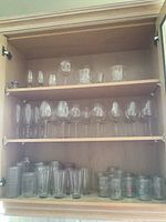 Top shelf containing various stemmed glasses of different shapes and sizes and some short glass containers