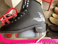 Black ladies Aurora Bladerunner ice skate side view with white feather graphic and pink blade guard