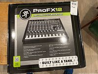 Front view of the product box showing the Mackie ProFX12 professional effects mixer with USB, highlighting key features and rugged design.