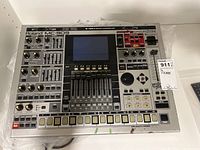 Front view showing full control panel with pads, faders, knobs and LCD display.