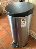 Simple Human stainless steel step trash can with black lid and foot pedal shown on floor