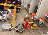 Overview photo showing the Playmobil MAXX7 yellow crane standing, Wheely Bug ride-on toy in front, transparent containers with toys, and boxes with wooden blocks.