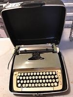 Front view of Smith-Corona Galaxie typewriter in carrying case, showing keyboard, platen knob, and ribbon area