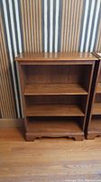 Front view of maple wood bookcase showing three shelves and scalloped bottom trim.