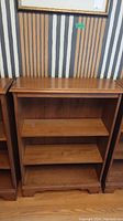 Front view showing the three open shelves and decorative bottom edge of the maple bookcase.
