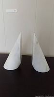 Front view of two tall triangular white marble bookends with smooth finish and some chips.