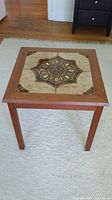 Full view of the square wooden side table showing the geometric ceramic tile inset on top and four straight legs.