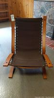 Full front view of the MCM lounge chair showing brown sling seat with no cushion.