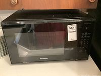 Front view of black Panasonic microwave oven with door closed, showing control panel and brand name