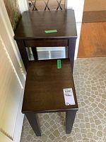 Top view of two mahogany nesting tables stacked, showing worn dark wood finish and simple rectangular design, taped price label visible on smaller table.
