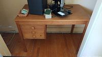 Wood desk with three dovetailed drawers on left, with square wooden drawer pulls and flat smooth top with a vintage sewing machine on top (not included).