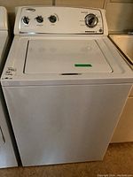 Front view of white top-load washing machine with lid closed and control panel visible
