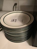 Stack of nineteen Wedgwood dinner plates showing underside with label.