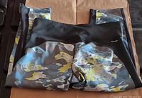 Folded Adidas camo pattern 3/4 leggings showing camo print and black waistband/edge