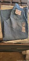 Folded Gloria Vanderbilt jeans showing branded label on back pocket and tags indicating size and model.