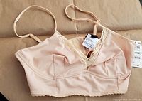 Front view of almond latte colored bralette with floral lace trim at neckline and bottom edge, size large with original tags attached.