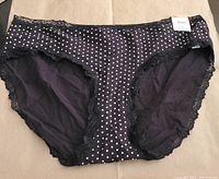 Front view of black Jenni hipster underwear with white polka dots and black lace trim. Item is new with tag visible.