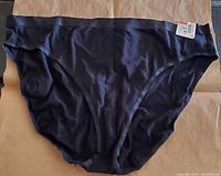 Front view of the deep black hi-cut bikini underwear with size tag visible, showing smooth fabric and cut style.