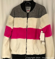 Front view of Kensie girl sweater, showing black and white checkered top portion, cream and hot pink color-blocked faux fur, black ribbed collar, and front zipper.