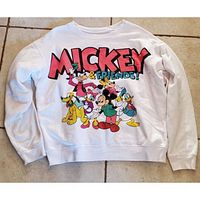 Front view of white pullover sweater with colorful vintage Mickey Mouse and friends graphic print.