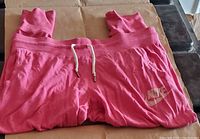 Front view of pink Nike sweatpants showing logo and drawstring waistband.