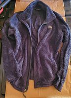 Front view of black plush fleece jacket with full zip and The North Face logo on left chest