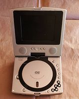 Front view of open portable DVD player showing screen, speakers, DVD tray, and control buttons