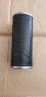 Front view of the black cylindrical portable speaker with mesh grill and silver metal top and bottom caps.