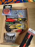 Box with assorted hand tools including screwdrivers, precision bits, pliers, and hex keys