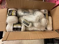 Open box filled mainly with white skeins of Phentex yarn, some still wrapped in plastic packaging.