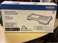 Box of Brother TN-450 toner cartridge showing front with branding, compatibility, and toner yield info.