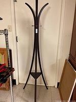Full view of the dark wood floor coatrack showing curved hook tops and tripod base