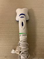 View of Dr. Scholl's branded electric handheld massager with power cord wrapped around the handle.