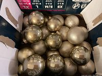 Box of mostly shiny gold Christmas ball ornaments with some matte finish ones, various sizes.