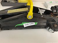 Side view of black hydraulic floor jack with yellow handle and label Lot 120.