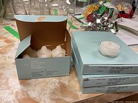 Photo showing three light blue boxes with white votive candles inside and one tea light candle on top.