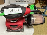 Skil red orbital electric sander with pressure control and micro-filtration dust collector attached, showing front and top sides.